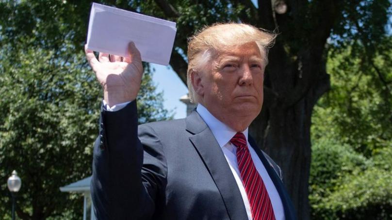 President Trump holding up a piece of paper