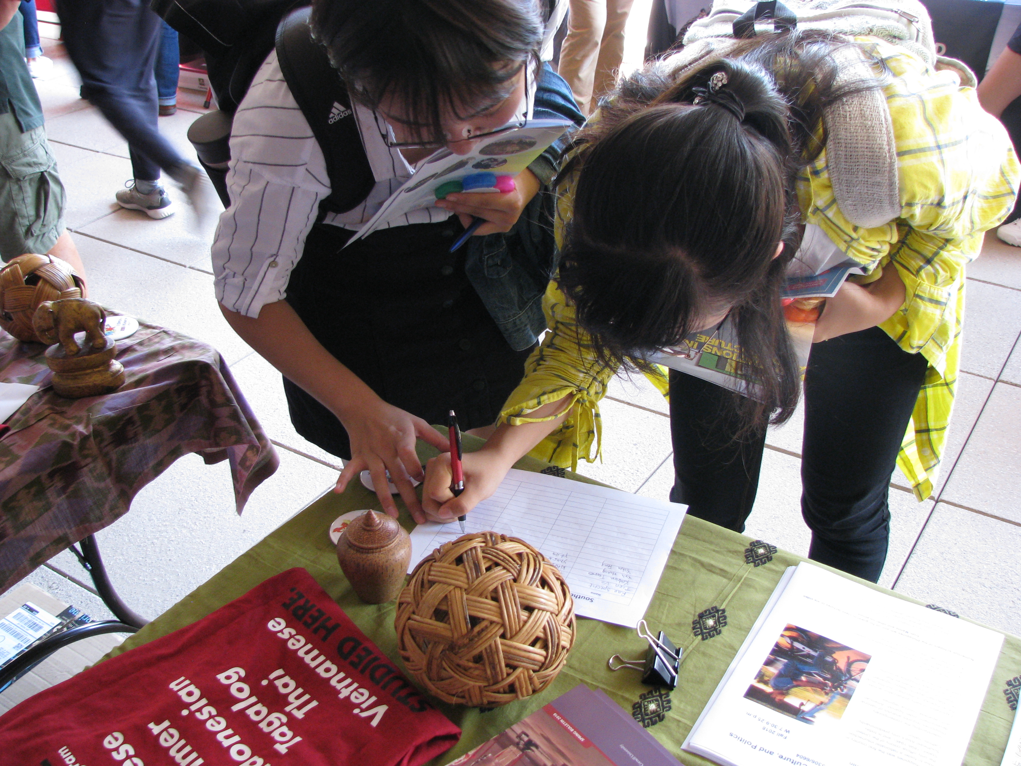 Two students signing up for more information at a table advertising the six Southeast Asian languages taught at Cornell.