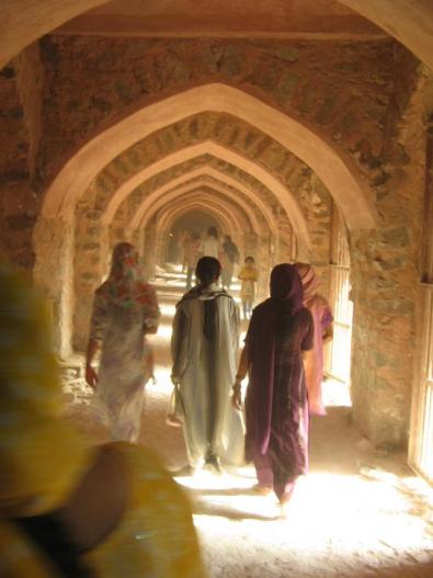 Woman walking under arches, India