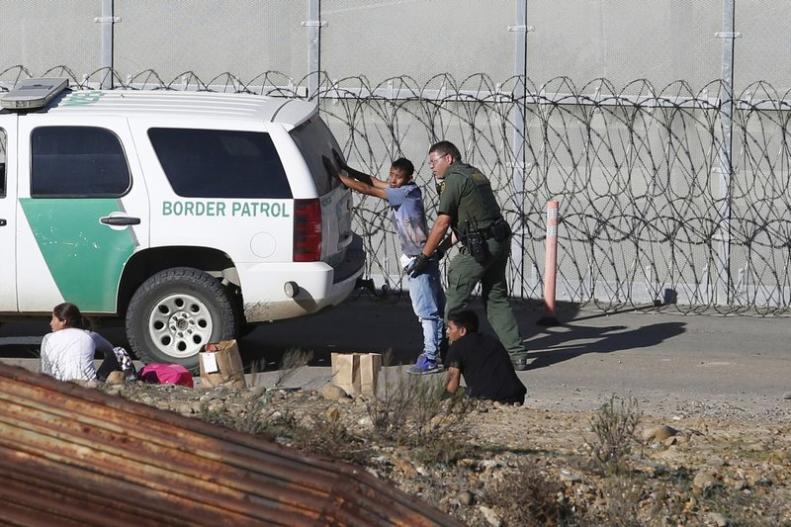 Border patrol agent patting down man
