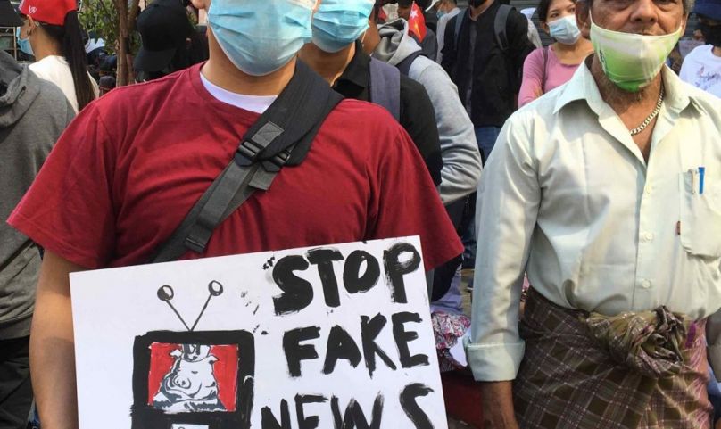 Protestors in Yangon carrying a sign saying "Stop Fake News" in English.