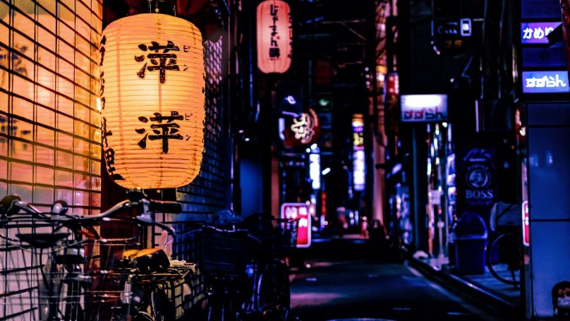 Japanese lanterns glow against a navy blue evening city street
