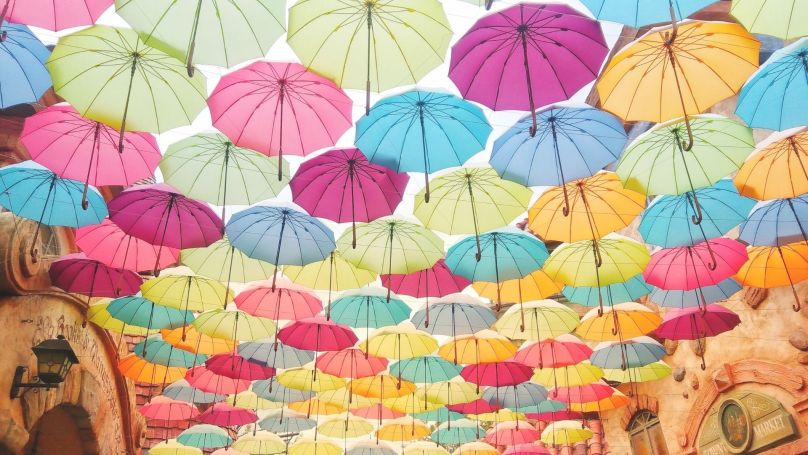 Multi-colored umbrellas hang overhead filling the screen