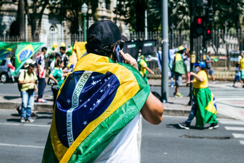 Brazilian flag worn as a cape by man at political protest or patriotic event