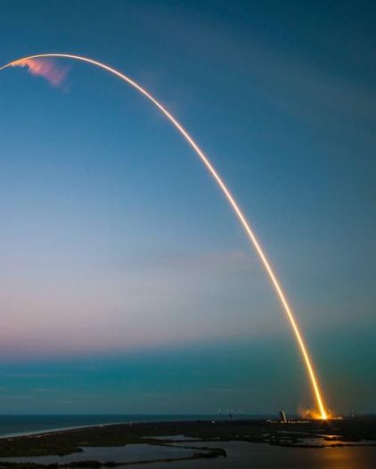 trail of rocket launch arches into sky above