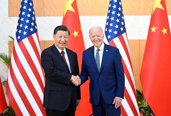 President Xi Jinping and U.S. President Joe Biden shake hands in front of China and US flags