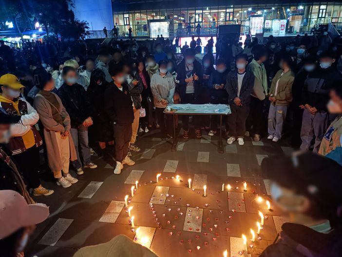 Students hold candlelight vigil to remember victims of Ürümqi apartment fire who could not escape burning building due to covid lockdowns 