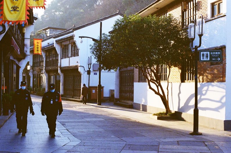 Two Chinese police officers walking through deserted neighborhood in Hangzhou