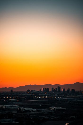 sunrise glow over Phoenix skyline with mountains in the distnace