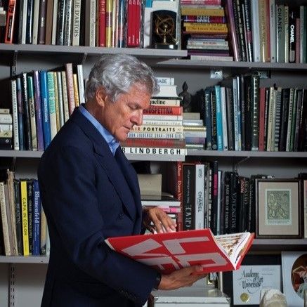 Side profile of Alain Elkann reading a book while surrounded by books