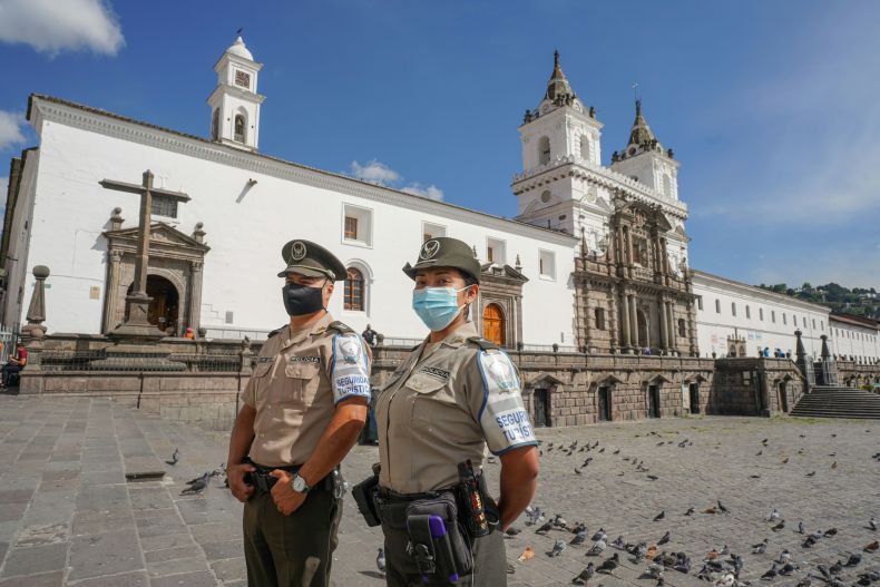 Police stand together in an open courtyard.