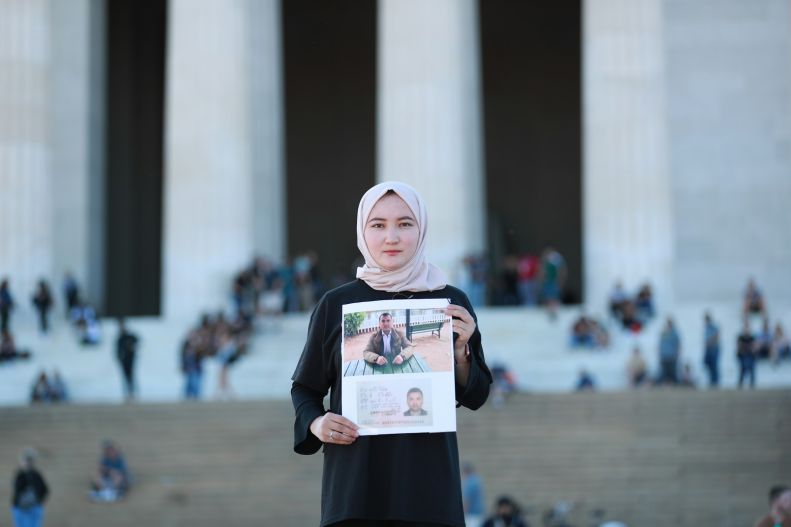 Woman wearing hijab and holding family photo, Uyghur protest, Lincoln Memorial, Washington, DC, Oct. 2021 
