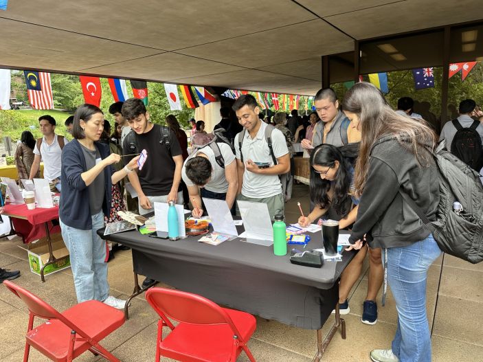 Students gather around a table at the International Fair.