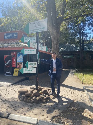 Intern stands next to a sign with many arrows pointing in all directions.