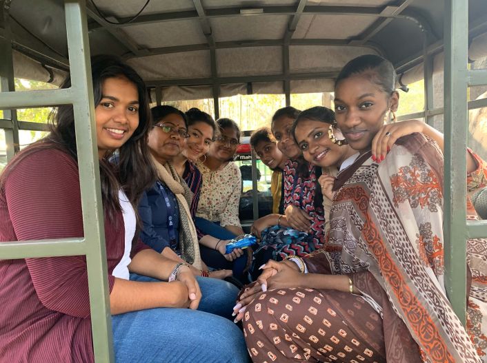 Kamala Eyango MPS ’20 smiles with a group of people in India, seated in the back of an open car.