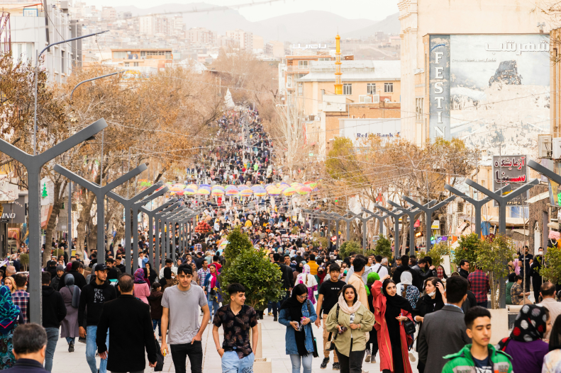 People walking on a large thoroughfare in Iran.