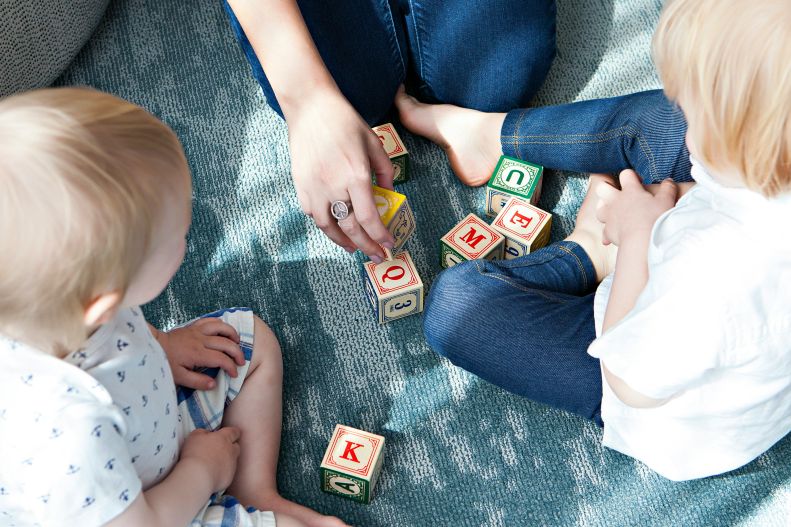 Two toddlers playing with ABC blocks