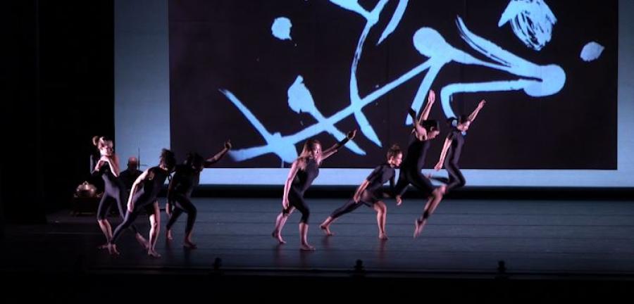 Dancers leap in front of a projection of Tong Yang-Tze's calligraphic art
