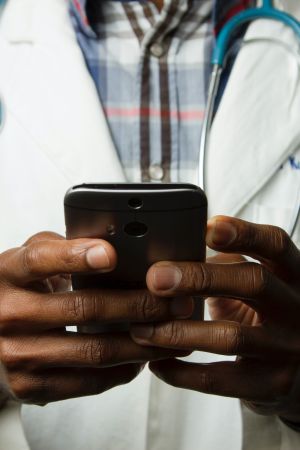 Doctor in lab coat wears stethoscope and holds smart phone