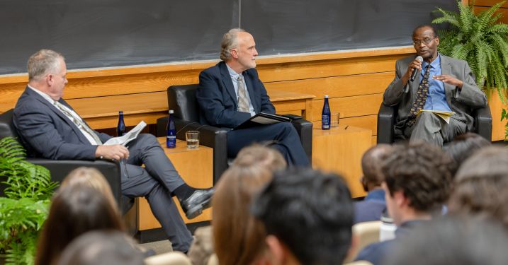 Chris Barrett speaks into a microphone next to Paul Kaiser and Chris Barrett.