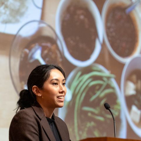 Researcher speaks in front of a large photo of different vegetables and dishes