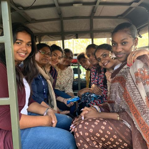 Kamala Eyango MPS ’20 smiles with a group of people in India, seated in the back of an open car.