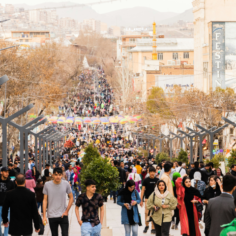 People walking on a large thoroughfare in Iran.