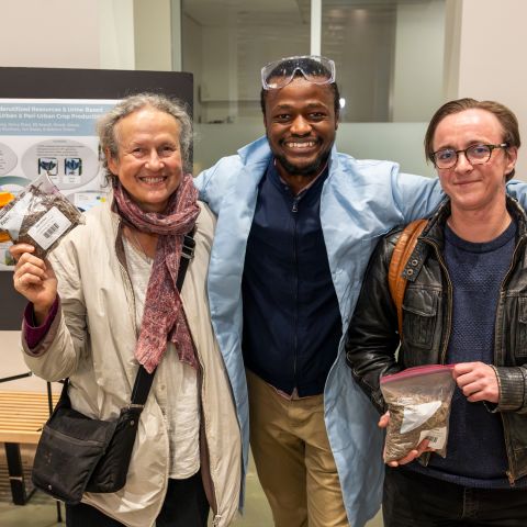 Laidlaw scholars and their faculty mentor smile together in front of a research poster.