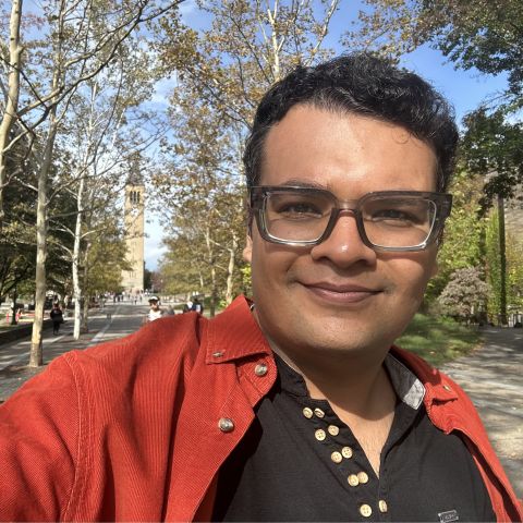Man in orange shirt stands in front of empty sidewalk. 