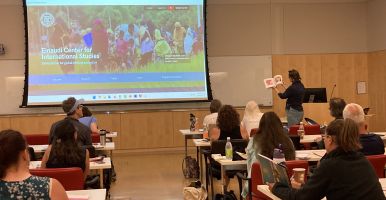 Lecturer holds up a book to a classroom full of teachers.