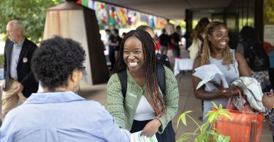 A student smiles and shakes the hand of a staff member at the International Fair.