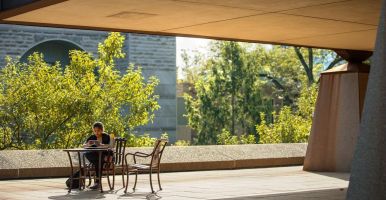 Student works at a table outside Uris Hall.